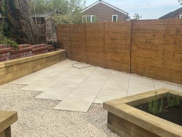 A backyard with tiled patio and wooden fence.