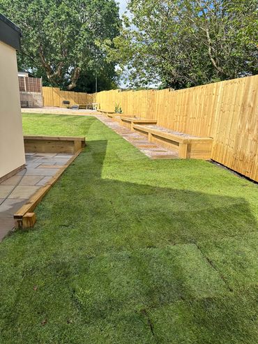 Newly landscaped backyard with fresh sod and wooden fencing.