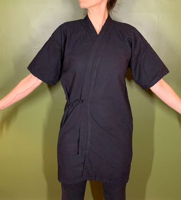 Person wearing a black kimono-style robe with arms extended.