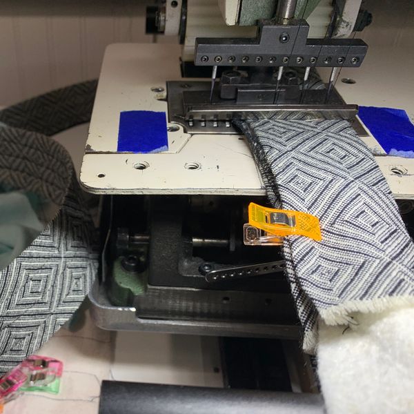 A close-up process shot of a piece of a garment with a geometric pattern being sewn