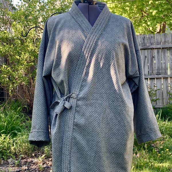 Gray patterned robe displayed on a dress form outdoors.