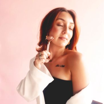 Woman using a facial roller on her cheek, eyes closed in relaxation.
