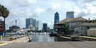 View of a city skyline with waterway and boats under a partly cloudy sky.