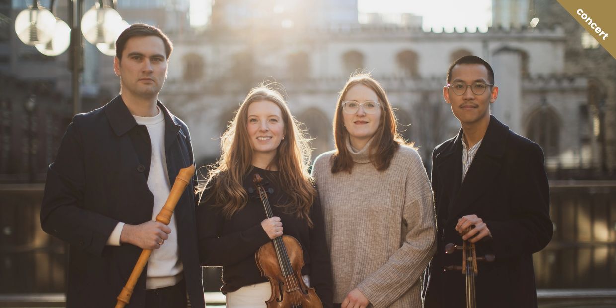 A group of four musicians posing outdoors with their instruments.