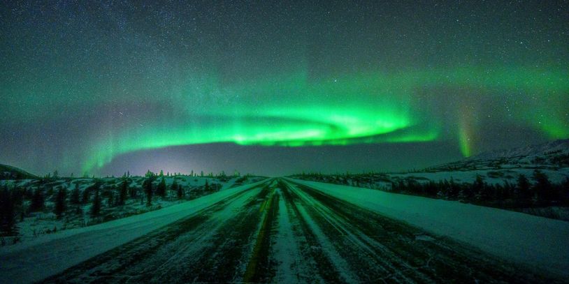 Image of the Aurora with the glow reflected on the road