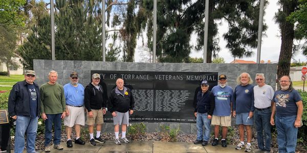 Group of men standing in front of Torrance Veterans Memorial wall.