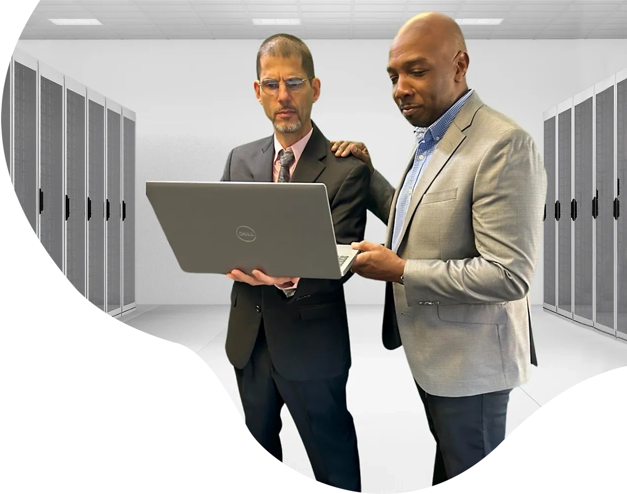 David and Jamal viewing a laptop with server cabinets in the background.