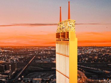 Tall skyscraper illuminated at sunset with two antennae.