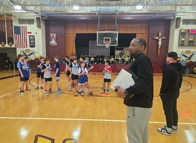 Youth basketball game with coaches observing.