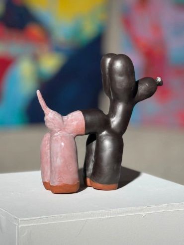 Abstract ceramic sculpture resembling a playful dog with mixed colors.