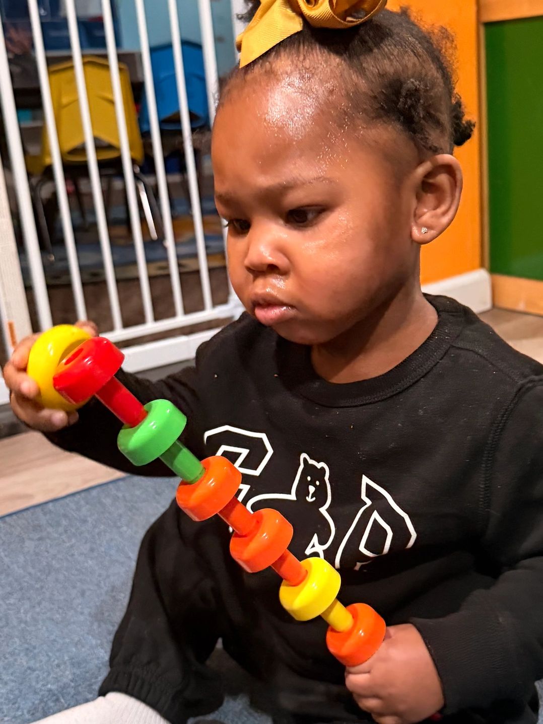 Young child focused on colorful toy in indoor play area.