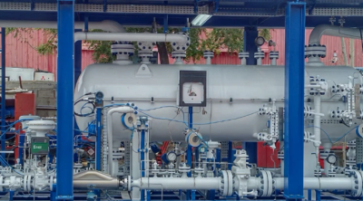 Industrial piping and machinery setup under a blue framework.