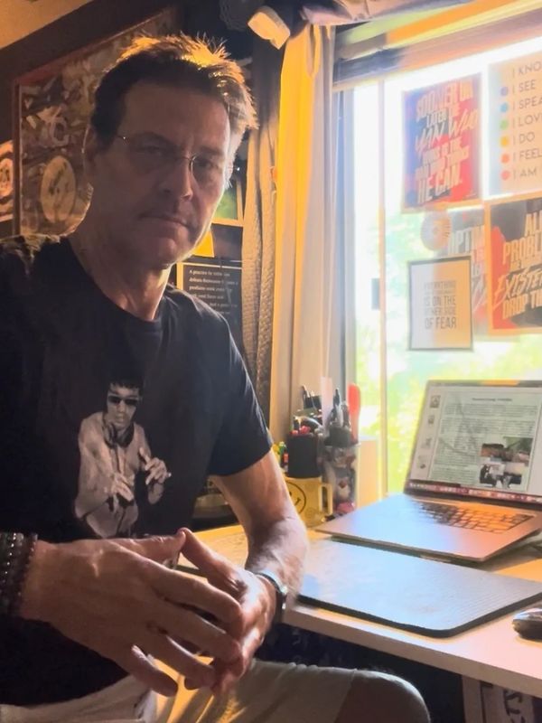 Man sitting at a desk with a laptop in a room filled with motivational posters.