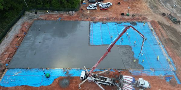 Workers pouring concrete on a large construction site.