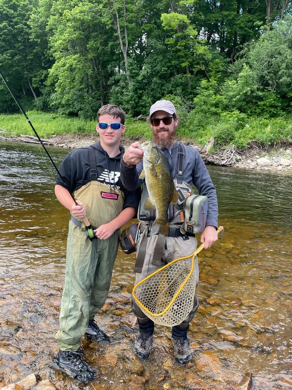 Fly fishing guide John Ruff holding a bass one of his clients caught in the Adirondacks