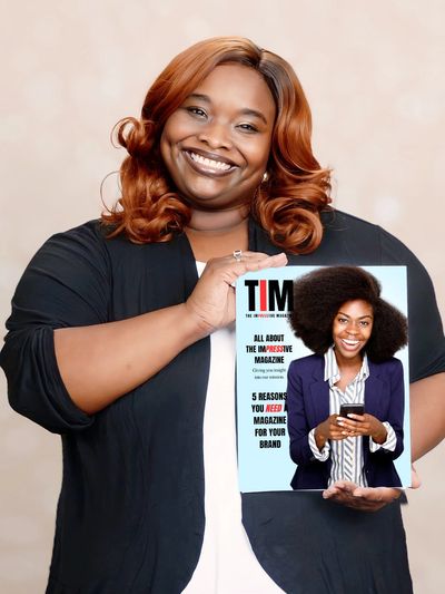 Smiling woman holding a magazine featuring a confident woman with natural hair on the cover.