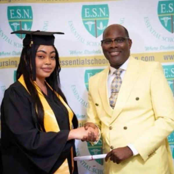 Graduate shaking hands with a man in a yellow suit during a ceremony.