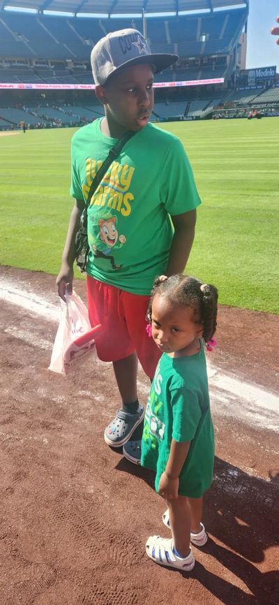Two kids in green shirts at a sports stadium.
