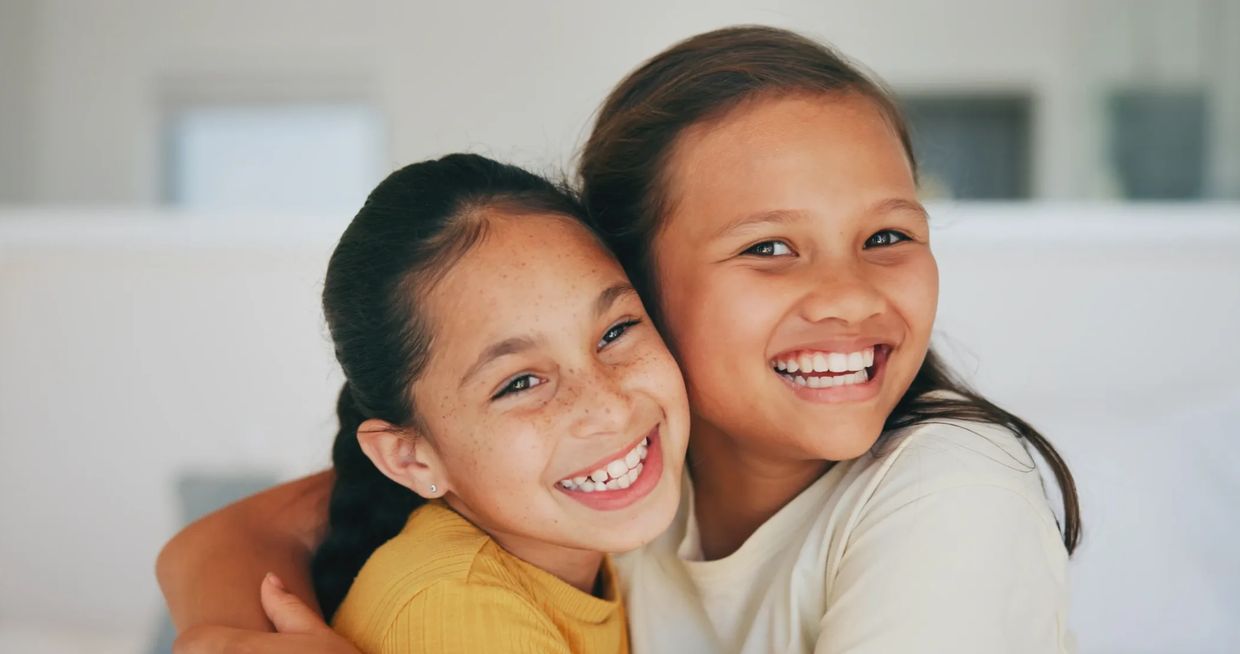Two girls joyfully hugging and smiling.