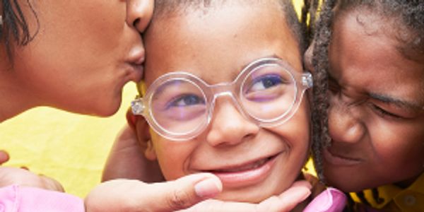 Child with glasses being kissed on the cheek.