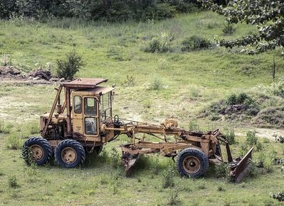 a old scrap road grader in a field waiting to be restored