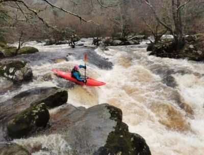A person kayaking on a rapid river.