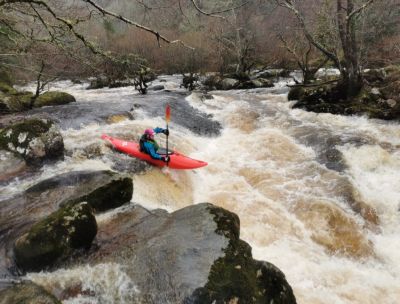 Person kayaking down a rapid river section.