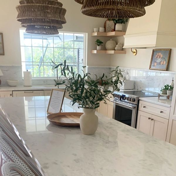 Bright kitchen with marble countertops and wicker pendant lights.