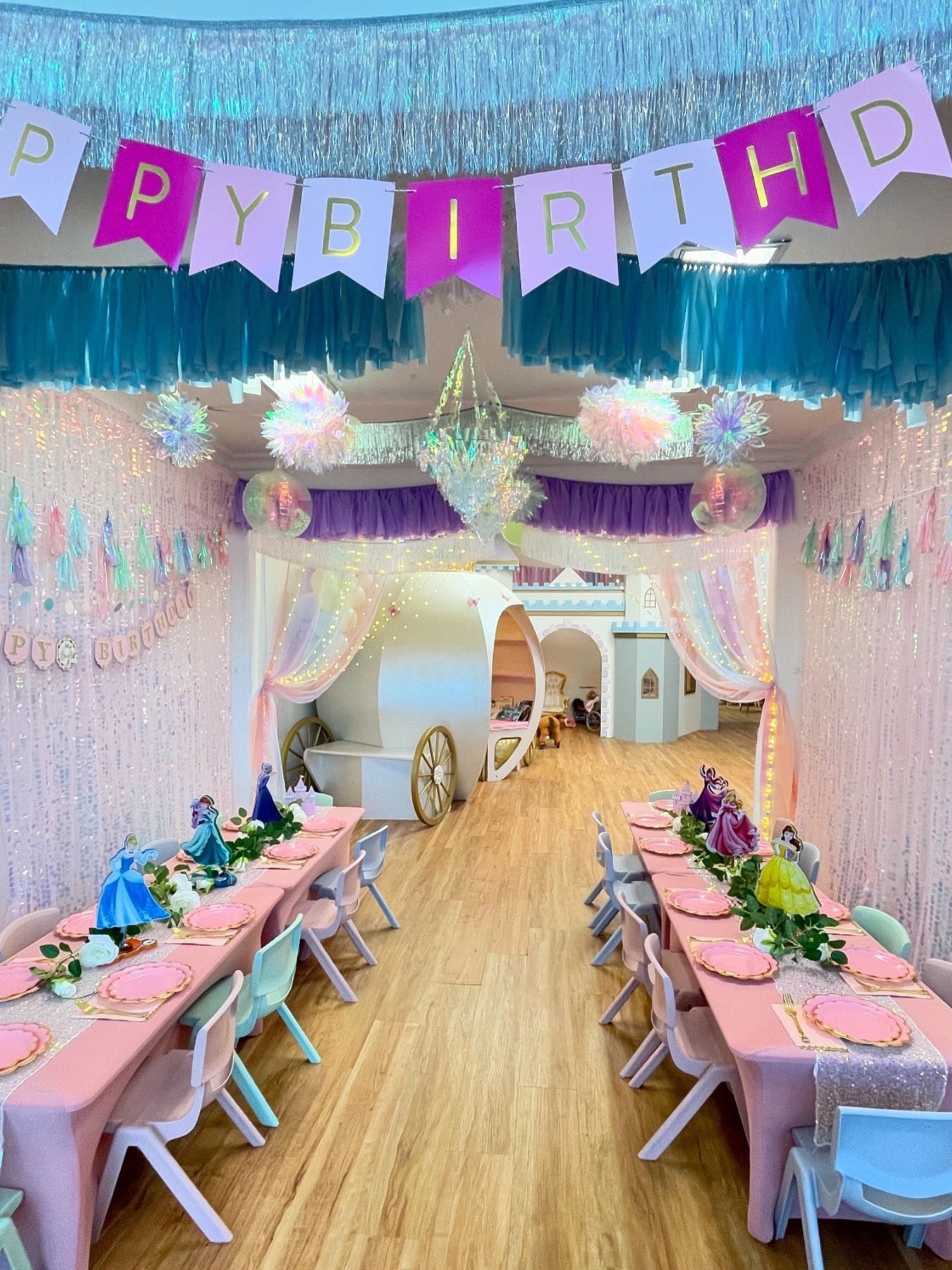A princess-themed birthday party setup with long tables and carriage.