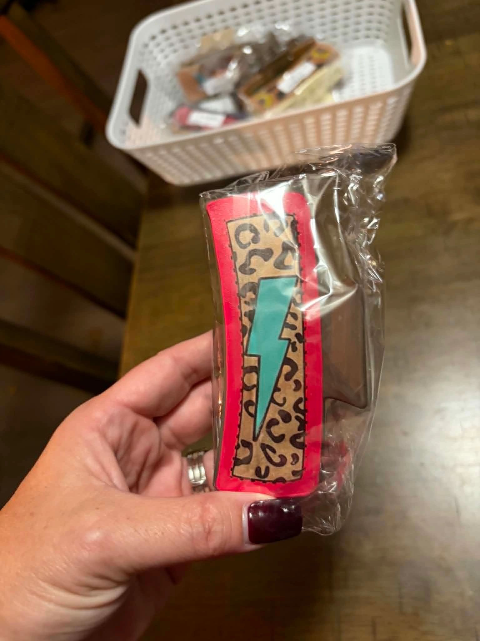 Hand holding a packaged item with a lightning bolt and leopard print design.