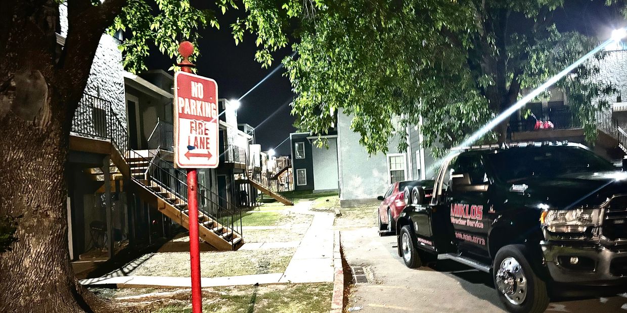 Miklos Tow Truck removing car in Tulsa fire lane private property and impound enforcement at night.