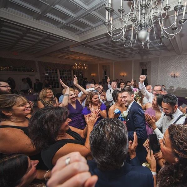 A joyful wedding celebration with guests applauding the bride and groom.