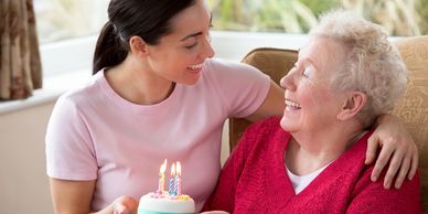 Caregiver smiling at older woman both in pink shirts