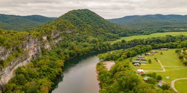 A winding river runs beside forested hills and a small community of houses.