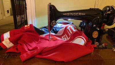 Vintage Singer sewing machine stitching red fabric.