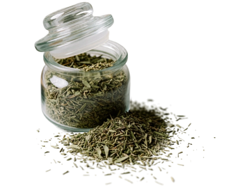 Glass jar with dried herbs and spilled herbs beside it.