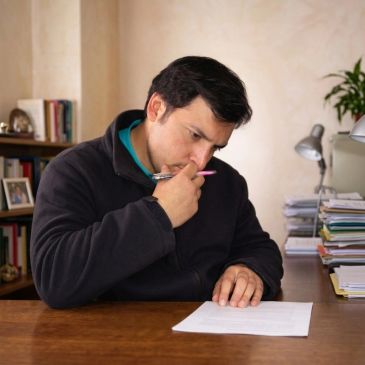 Hombre concentrado leyendo un documento en su escritorio.