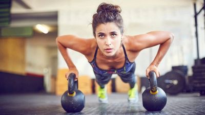 Woman doing push-ups using kettlebells.