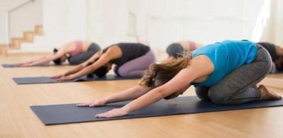 People practicing child pose in yoga class.