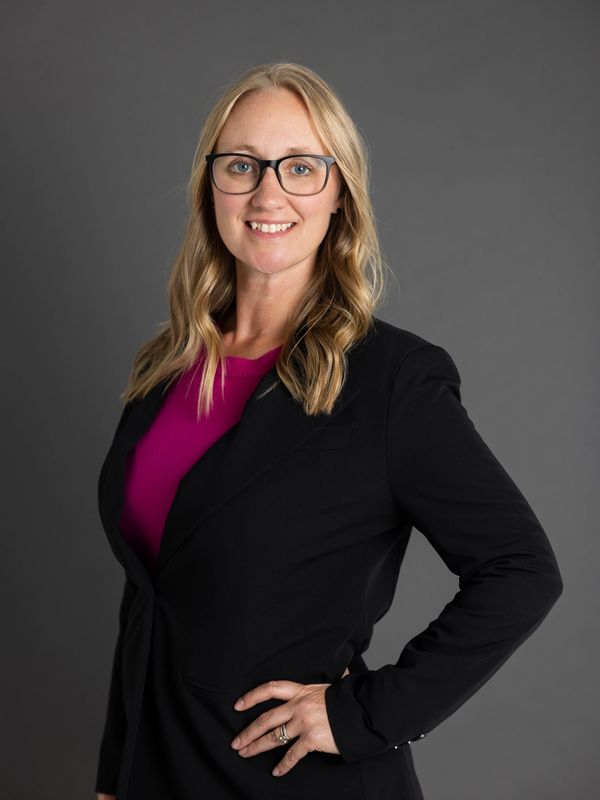 Dr. Jen Mimish, Women's Health Nurse Practitioner in a bright pink shirt with suit jacket, glasses