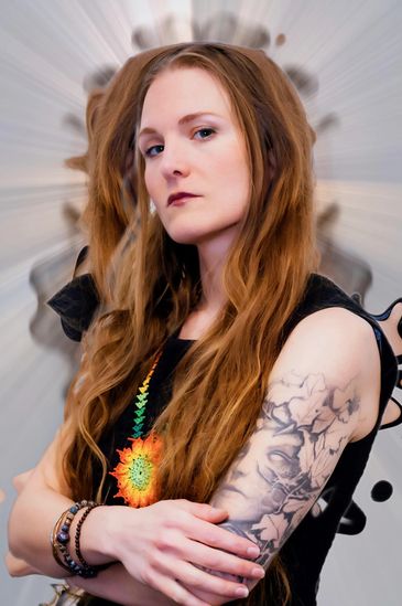 Confident woman with long hair and detailed tattoo on her arm.