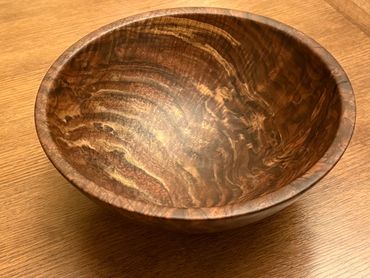 Handcrafted wooden bowl with rich grain patterns on a wooden surface.