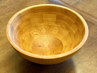 A wooden bowl with a smooth finish placed on a wooden table.