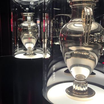 Reflective glass vases artfully displayed in illuminated cases.
