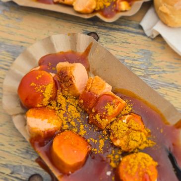 Currywurst pieces topped with curry powder and sauce on a paper tray.