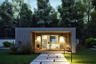 Modern tiny house illuminated at dusk with pathway.