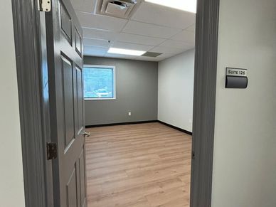 Empty office room with wooden floor and gray walls.