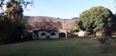 Casa blanca con amplio jardín y árboles.