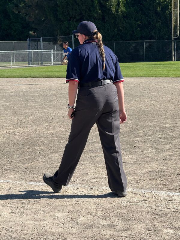 Umpire standing on a baseball field in uniform, watching the game.