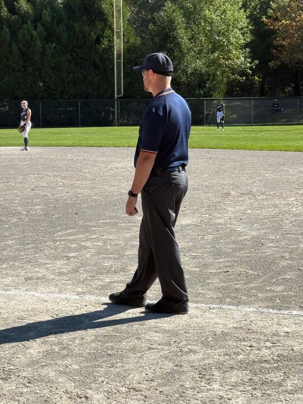 Baseball umpire standing on the field observing the game.